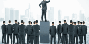 A businessman stands elevated on a pedestal above others in suits.