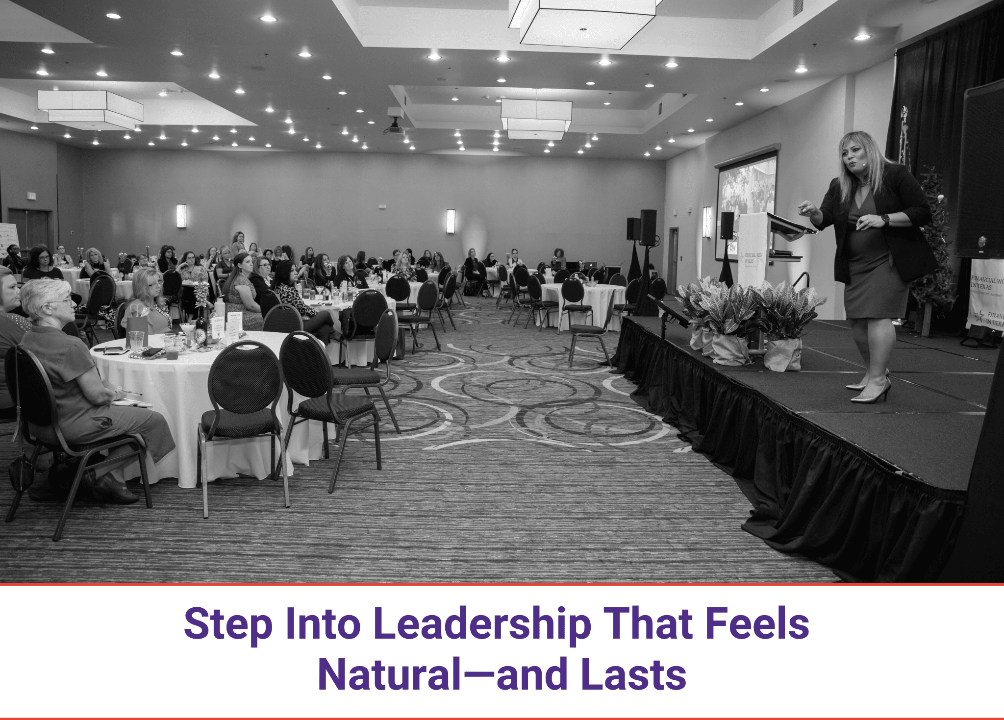 A conference room with attendees and a speaker on stage.